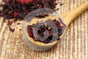 Karkade tea. Hibiscus tea leaves in wooden spoon isolated on wooden background. File contains clipping path. Top view. Selective