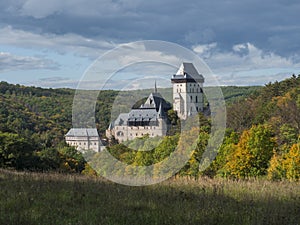 Karlstejn gothic state castle near Prague, the most famous castle in Czech Republic with grass meadow and autumn colored trees and