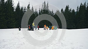 KARPATY, HOVERLA, UKRAINE - MARCH 2023: A group of tourists in raincoats with backpacks climb a mountain in the rain and