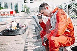 Karting racer sits on a tire, outdoor kart track