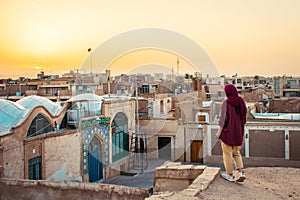 Kashan, Iran - 10th june, 2022: woman enjoy Kashan city buildings rooftops background with sunset panorama Explore iran historical