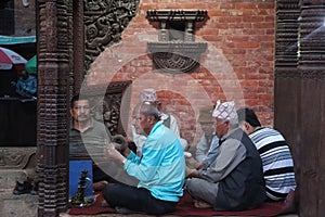 A group of Nepali men singing Hindu bhajan while using holy musical instruments sitting on the ground.