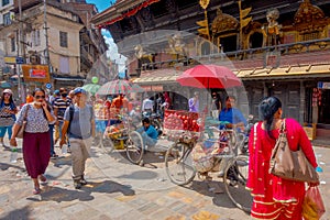 KATHMANDU, NEPAL OCTOBER 15, 2017: Unidentified people walking close to a bike with some fruits inside of a metallic