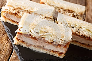 Katsu Sando sandwiches with pork cutlet, tonkatsu sauce and cabbage closeup on a slate board. horizontal photo
