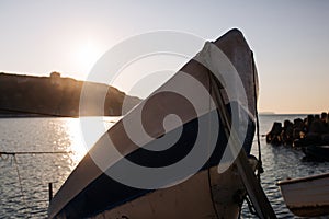 Kavarna, Bulgaria - September 2016: The bow of a fishing boat pulled ashore sticks out into the sky, sunrise as a background on