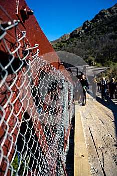 Kawarau Bridge, New Zealand, October 6, 2019: Close-up of the bridge fence with boys in the background preparing to bungee jump