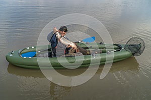 Kayak fishing. Fisherman caught pike fish on inflatable boat with fishing tackle at lake