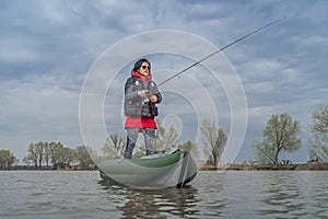 Kayak fishing at lake. Fisherwoman on inflatable boat with fishing tackle