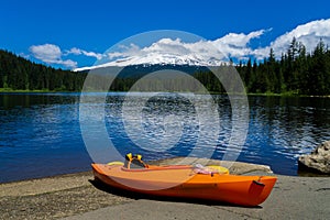 Kayak lying on the ground at Trillium Lake with the Mt. Hood in the background on a sunny day of early summer. Recreation and fish