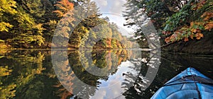 Kayak on mirror Lake with fall leaves changing to orange and red in the early part of wisconsins season change