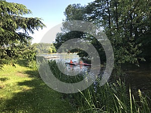 Kayak rowing. Children in lifejackets sail by canoe along the canal in the park.