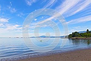 Kayak, seagulls, nautical vessels and snow mountain peaks in bay landscape on a sunny day.