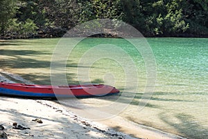 Kayak on the tropical white sand beach with sea waves. Clear water of sea waves on the beach.
