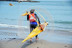 Kayaker carrying kayak towards sea