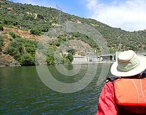 Kayaker in orange vest with hat in kayak on river with hills