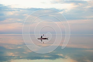 A kayaker swims along the estuary at sunset