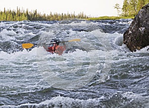 Kayaker turning over in whitewater