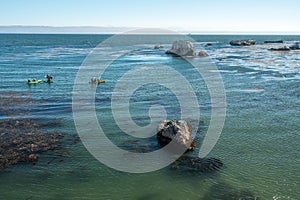 Kayaking along rocky shore, Pismo Beach, California