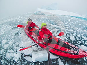 Kayaking in Antarctica, couple of kayakers doing travel selfie with icebergs