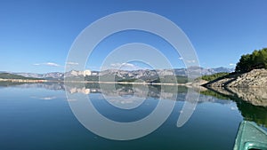 Kayaking on calm mountain lake. Panoramic view of landscape and reflections.