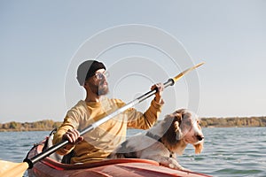 Kayaking with dogs: man rowing a boat on the lake with his spaniel.