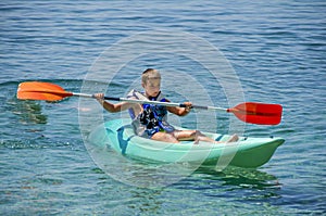 Kayaking lessons. Boy with life buoy suit in kayak lessons during summer vacations in an island of Greece.