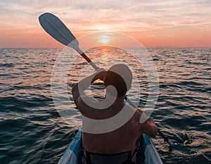 Kayaking. Man With kayak paddle at sunset sea Rowing to the Sun.