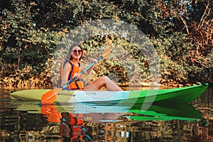 Kayaking on the river. A happy young tanned woman in a life jacket is floating in a kayak on the river. Concept of World