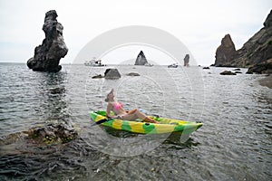 Woman kayak sea. Happy tourist takes sea photo in kayak canoe for memory. Woman traveler poses amidst volcanic mountains