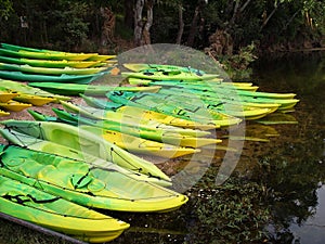 Kayaks and canoes on the river bank.