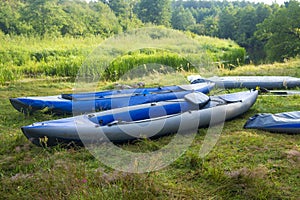 Kayaks for rafting along the river on the river bank. Boats or canoes on the river shore.