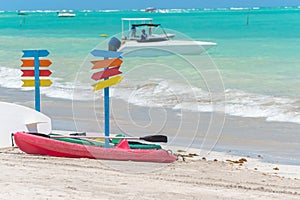 Kayaks on the sand of a beautiful beach and multiple colored signposts