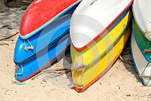 Kayaks stacked on sand beach. Colorful boats in front of sea coast.