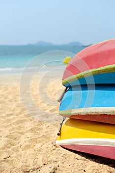Kayaks stacked on sand beach. Colorful boats in front of sea coast. Vacation and travel sport activity.
