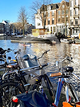 Kayaks on Amstel river in central Amsterdam and parked bicycles by the canal side