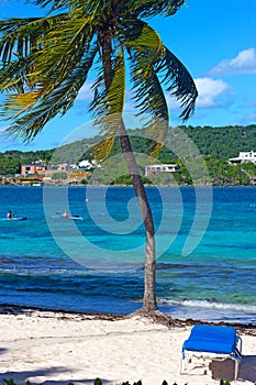 Kayaks in waters of a small bay on tropical island with sandy beach nearby.