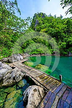 Kayangan Lake - Blue crystal water in paradise lagoon - walkway on wooden pier in tropical scenery - Coron island, Palawan,