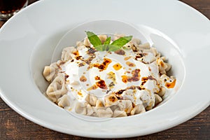 Kayseri ravioli or Kayseri Mantisi on a white plate on wooden table