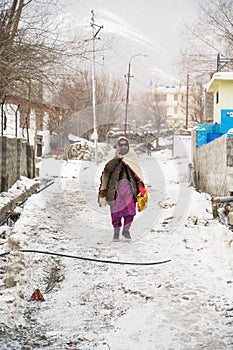 KAZA, SPTI, INDIA - Dec 14, 2019: An Old Lady walking in the middle of a Snow talking over the Phone