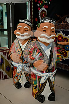 Kazakh national wooden figurines of girls in national costumes.Figures stand on a beige table on the background of national scarve photo