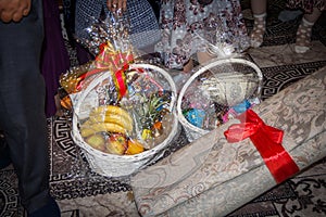 Kazakh traditions for kudalyk-matchmaking to give gifts. Carpet and basket with fruits and sweets. photo