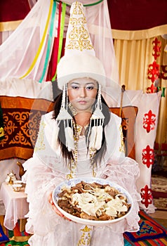 Kazakh woman in white national dress with national food - beshparmak