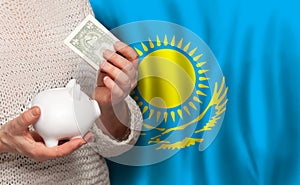 Kazakhstani woman with money bank on the background of Kazakhstan flag. Dotations, pension fund, poverty