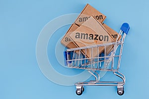 Modified photo of parcel with Amazon logo in the shopping cart on a blue background