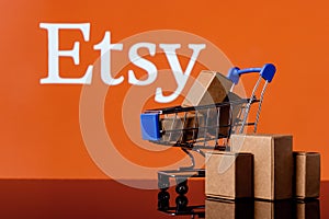 Shopping cart with parcels on the background of the Etsy logo
