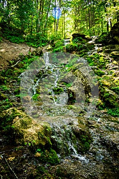 Kazu Grava waterfall in the middle of a beautiful green and lush forest illuminated by the sunlight in Latvia photo