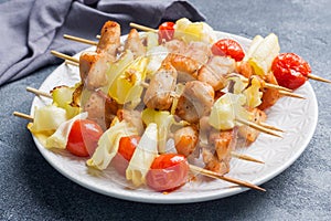 Kebab chicken, zucchini and tomatoes on skewers in a plate. Dark table