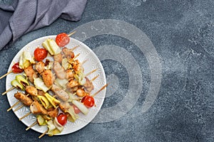 Kebab chicken, zucchini and tomatoes on skewers in a plate. Dark table Copy space