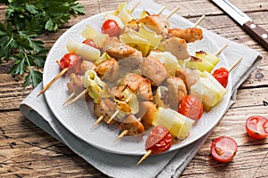 Kebab chicken, zucchini and tomatoes on skewers in a plate. Wooden table
