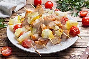 Kebab chicken, zucchini and tomatoes on skewers in a plate. Wooden table